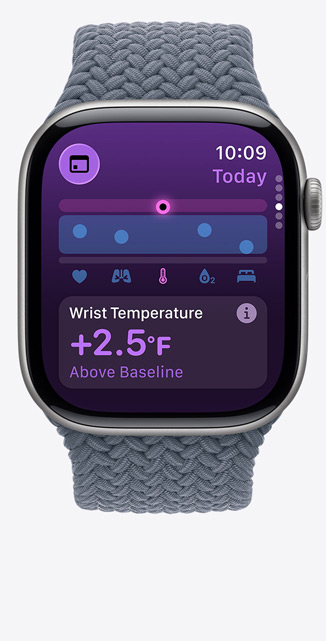 Apple Watch Series 11 med urkasse av skifergrå titan og flettet Solo Loop i ankerblå viser Vitale tegn-appen med et poengdiagram og en varsling om håndleddstemperatur over referansepunktet. På høyre side av urkassen vises Digital Crown