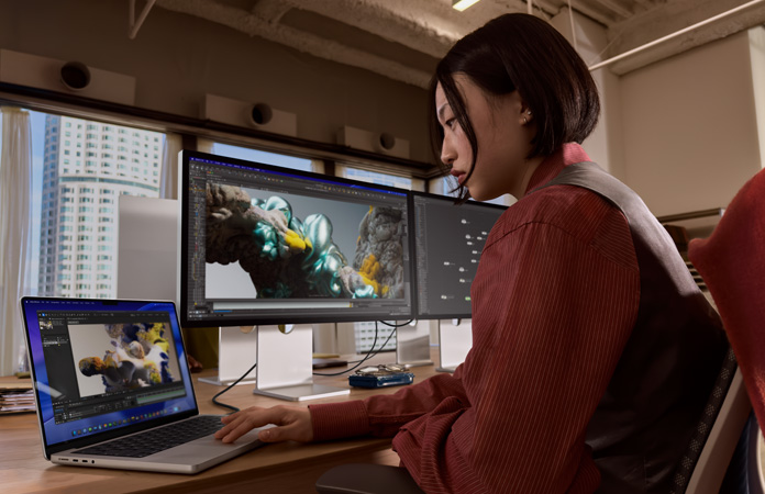 Egy Studio Display XDR-hez csatlakoztatott MacBook Prón dolgozó ember irodai környezetben
