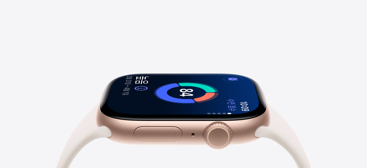 로즈 골드 색상 알루미늄 케이스와 수면 점수가 화면에 보이는 Apple Watch Series 11. 오른쪽 옆면 외장에 Digital Crown, 마이크, 측면 버튼 그리고 스타라이트 색상의 스포츠 밴드가 보입니다.