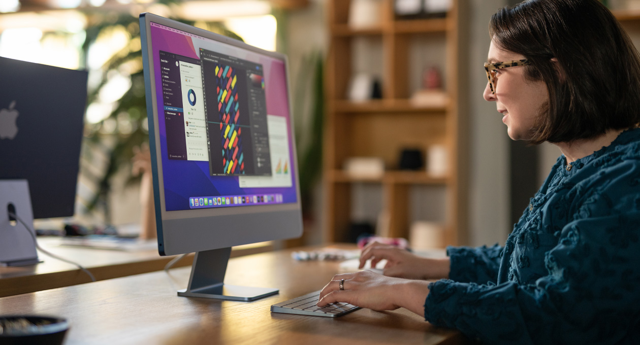 A person works at an iMac displaying a colorful design app in an office setting