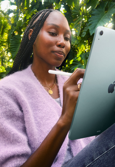 Una estudiante sentada al aire libre con un iPad y un Apple Pencil Pro.