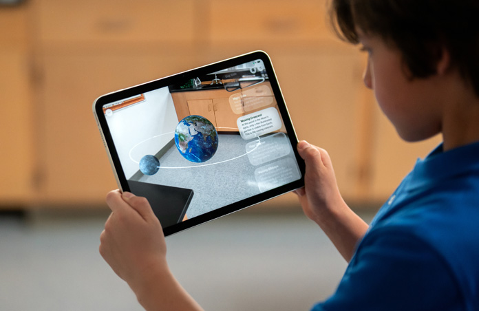 Student explores Augmented Reality on iPad, screen shows moon revolving around Earth as if in the classroom