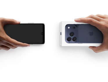 兩隻手在交換電話，左邊手拿著一部沒有包裝盒的 Android，右邊手拿著一部在包裝盒內的全新 iPhone 17 Pro。