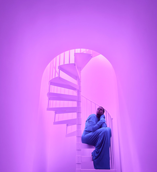 Photo en gros plan d’une femme assise sur un escalier en colimaçon illustrant les capacités photographiques en faible éclairage du système caméra pro