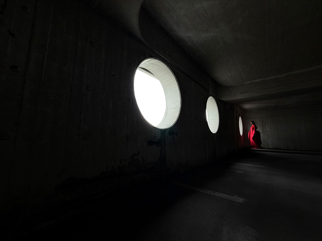 Femme portant une longue robe rouge photographiée dans une pièce vide. L’app Photos montre les distances focales pour illustrer les capacités du système caméra Pro : 13 mm