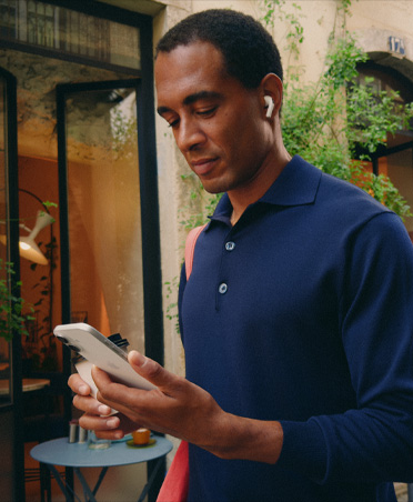 Person on a city street looking at their iPhone, maintaining seamless Wi-Fi connection across network transfers